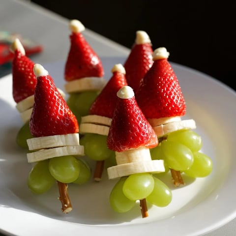 Vibrant Elf Hat Strawberry Skewers showcase a festive fruit snack; strawberries, bananas, and grapes look refreshing.