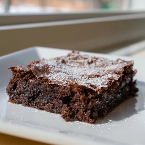 Fudgy brownie squares, dusted with powdered sugar, ready to be enjoyed as a sweet treat.