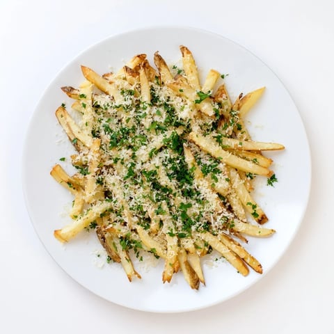 Golden-brown Truffle Parmesan Fries piled high, glistening with truffle oil and fresh parsley on a rustic plate.