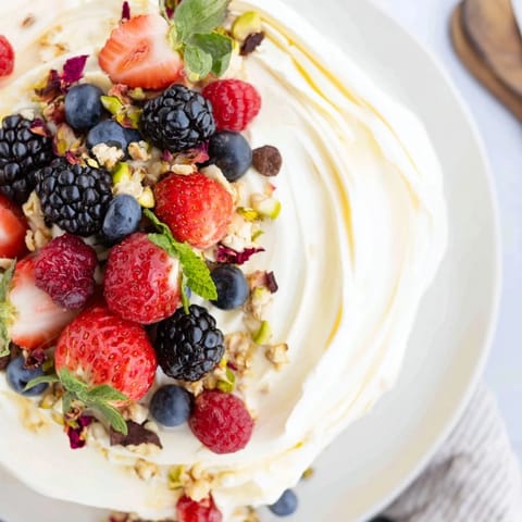 Colorful arrangement of whipped cream cheese and vibrant berries on a butter board.  