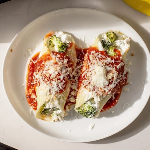 Golden-brown Cozy Broccoli Stuffed Manicotti, ready to eat, with a sprinkle of fresh herbs.