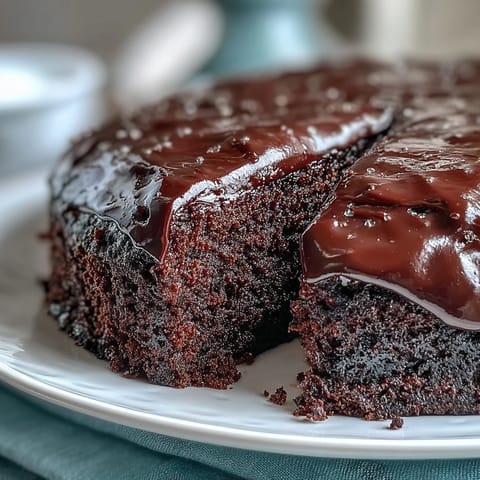 A slice of Easy Chocolate Fudge Cake reveals a dense, squidgy texture and silky smooth chocolate frosting.
