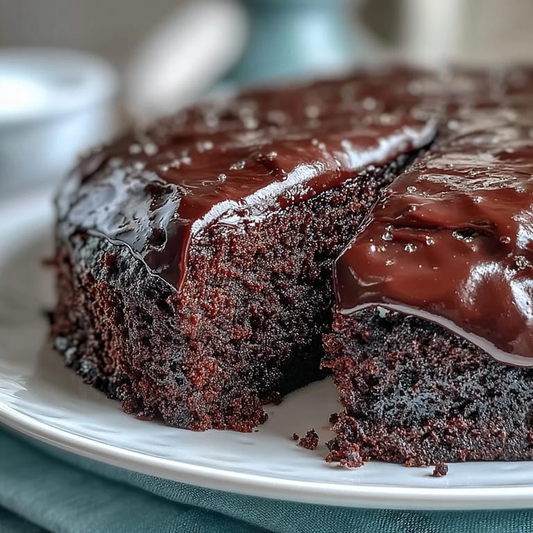 A slice of Easy Chocolate Fudge Cake reveals a dense, squidgy texture and silky smooth chocolate frosting.