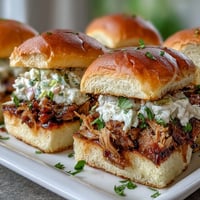 Delicious BBQ pulled pork sliders with tangy sauce and creamy coleslaw, perfect for baby showers and parties.