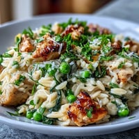 Creamy one-pot lemon orzo with tender chicken and sweet green peas, garnished with fresh parsley and Parmesan.  
