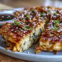 Crispy cabbage kimchi pancakes sizzling in a hot skillet, golden brown with tangy kimchi peeking through.